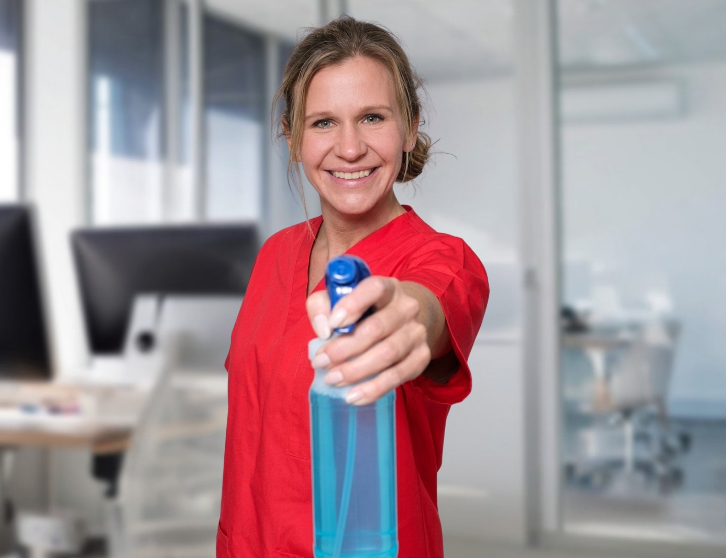 Reinigungskraft von CityCleaner mit Sprühflasche in der Hand bei der Büroreinigung in Gelsenkirchen
