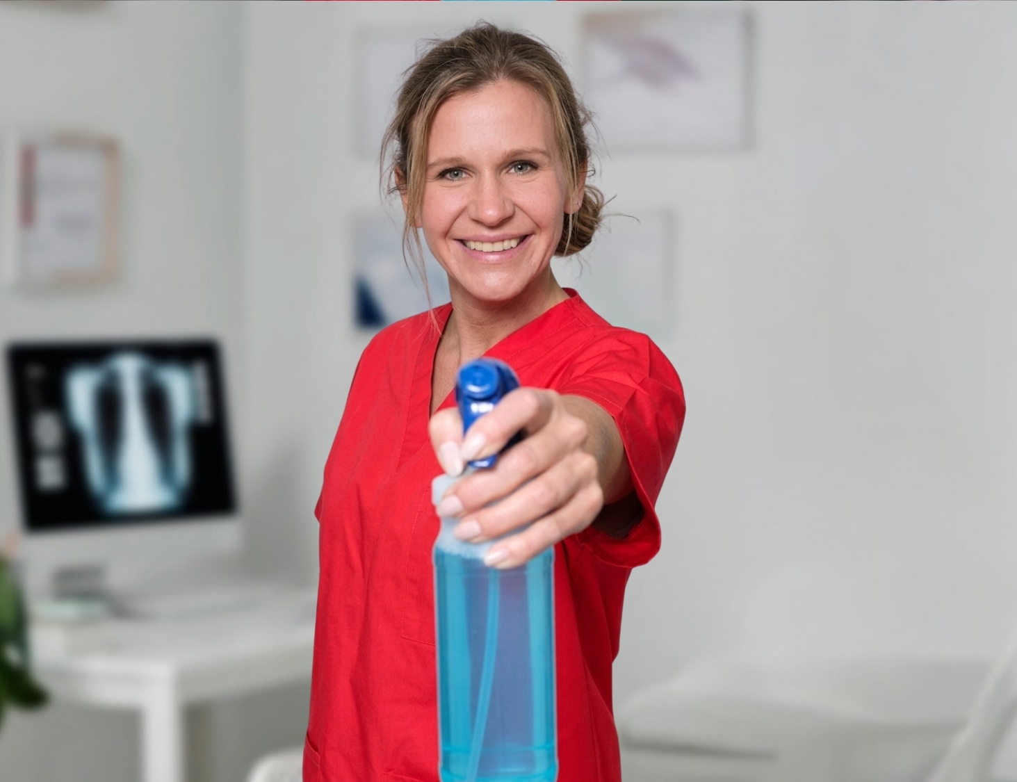 Reinigungskraft von CityCleaner mit Sprühflasche in der Hand bei der Praxisreinigung in Gelsenkirchen